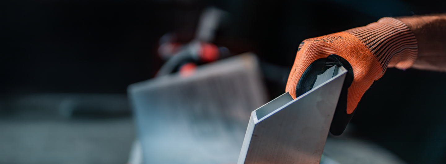 Pracovní rukavice s ochranou proti proříznutí RECA Protect při manipulaci s ostrým kovovým dílem