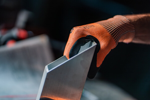 Pracovní rukavice s ochranou proti proříznutí RECA Protect při manipulaci s ostrým kovovým dílem